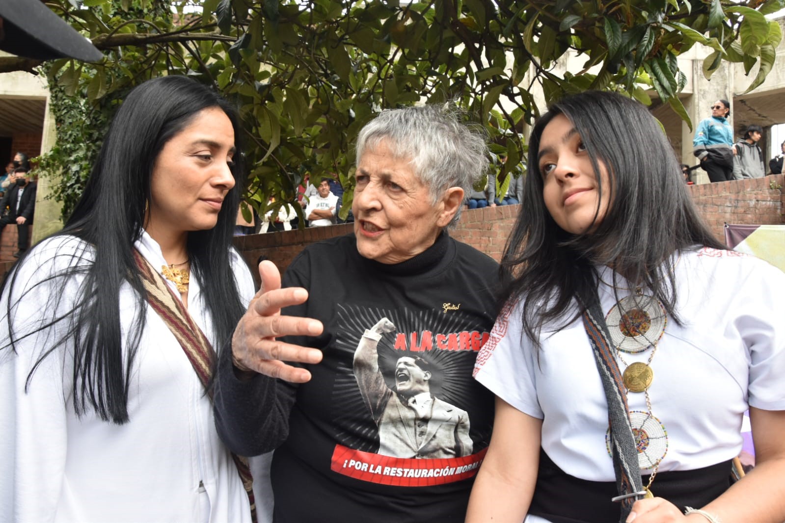 Fotografia en la que aparece la concejal Ati Quigua en una plaza acompañada de dos mujeres con las cuales conversa