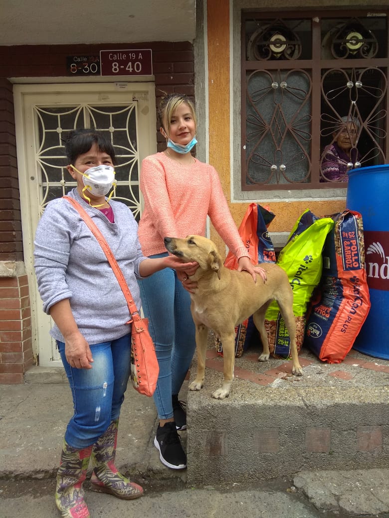 Mujeres con un perro y bulto de comida para animal