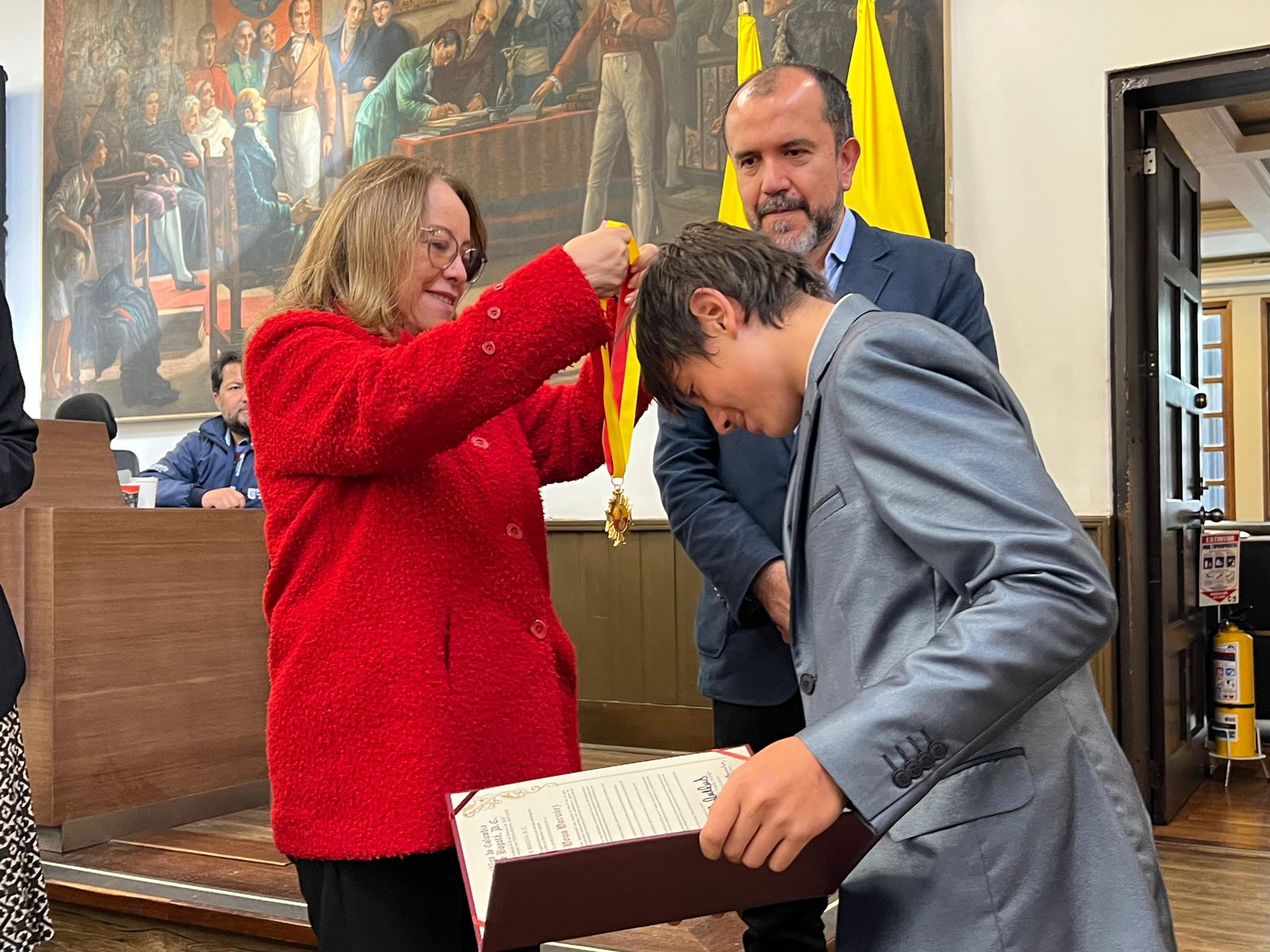 En esta fotografía la concejal colocando la medalla a Isaac