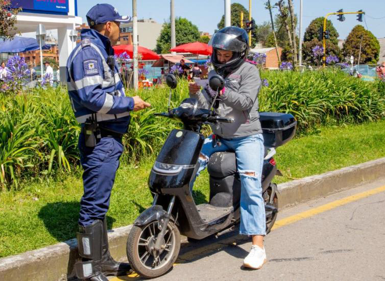 en esta fotografía un agente de transito conversando con un conductor de un vehículo electríco que ha detenido en la calle