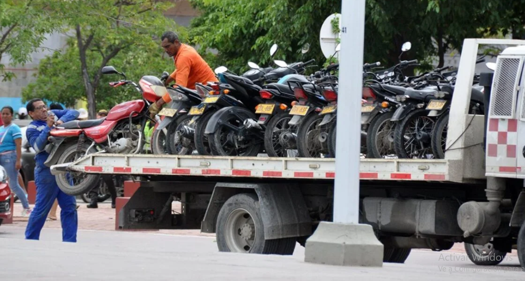 en esta fotografia apare una grua de planchón con muchisimas motos montadas sobre ella 