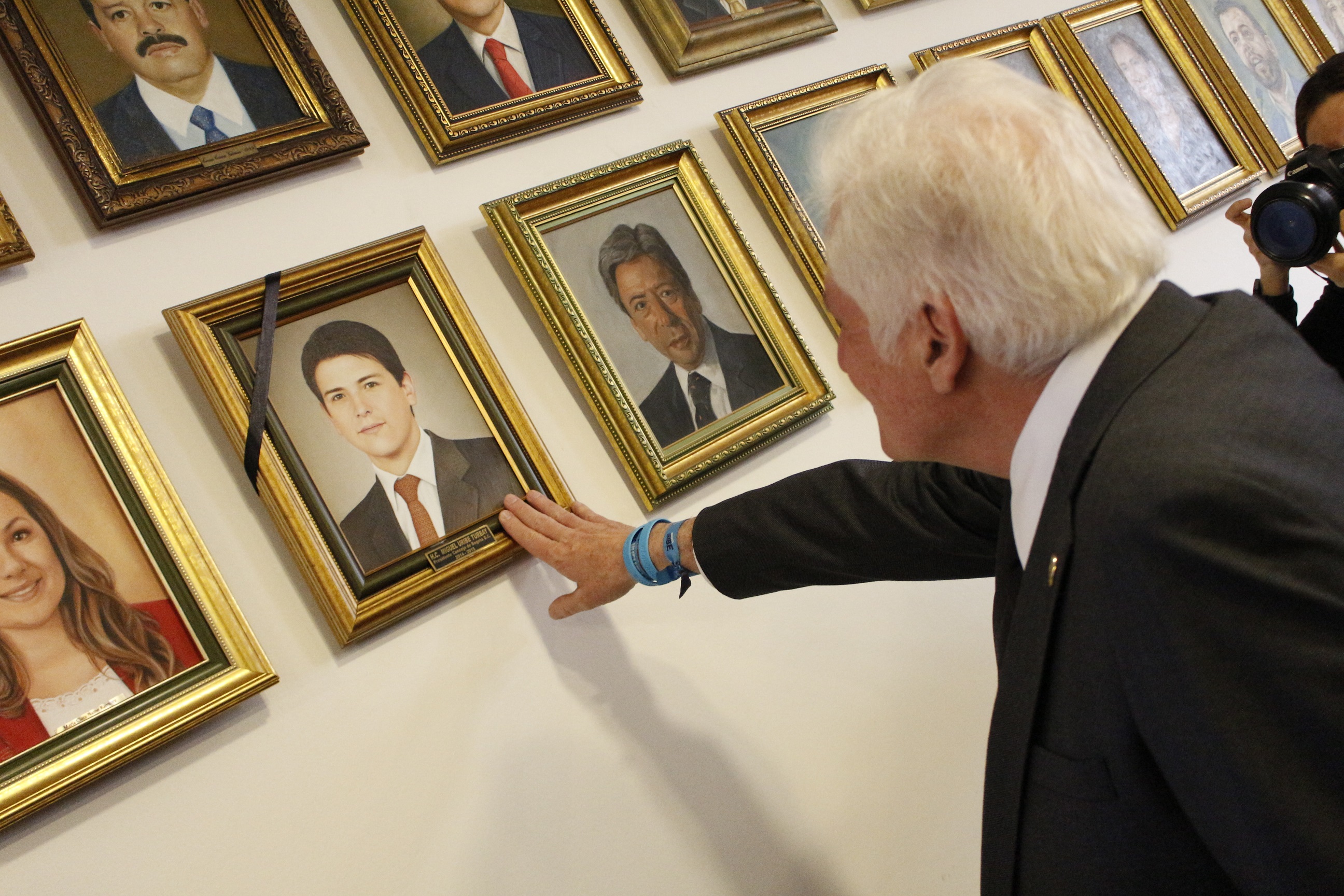 En esta fotografía Miguel Uribe Padre en el Salón Presidentes tocando el cuadro que tiene el retrato de su hijo